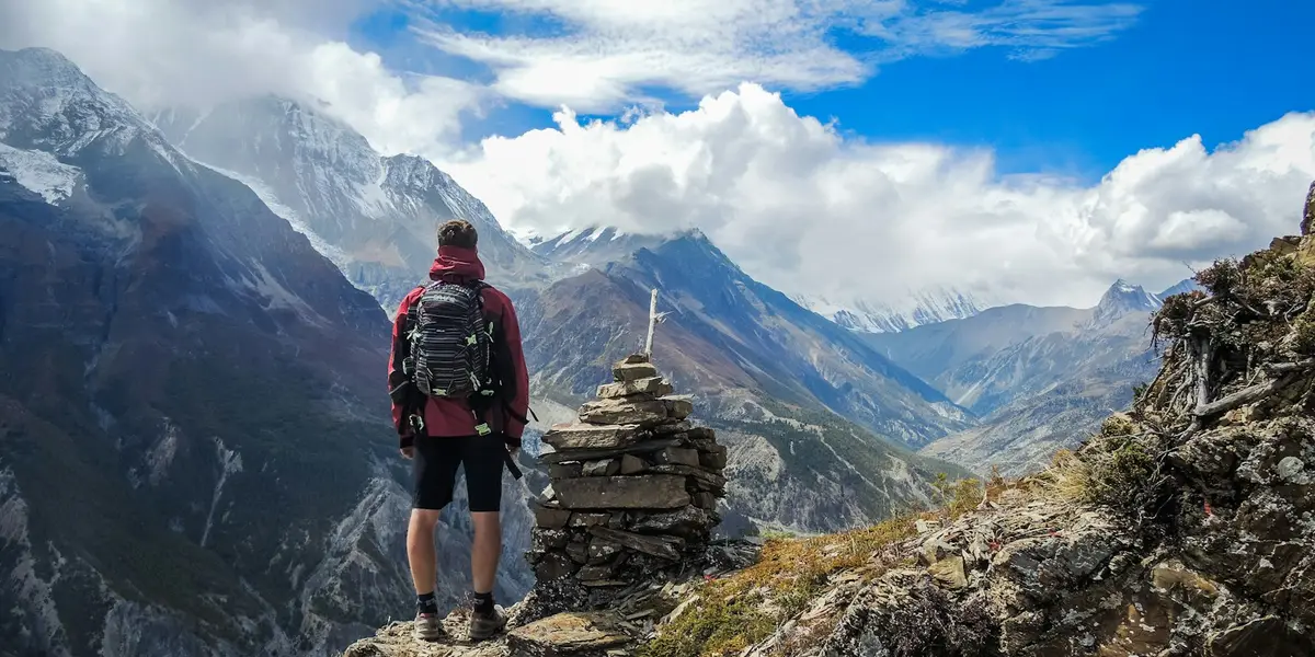 Wanderer mit Rucksack blickt auf eine Berglandschaft